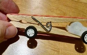 wrap the rubber band around the back of the vehicle and fasten it to the frame or rear axle